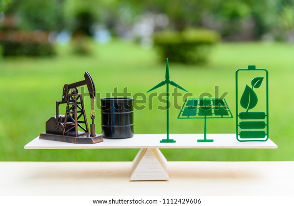 Fossil fuel vs renewable / future clean\
alternative energy concept : Petroleum pumpjack, crude oil drum\
barrel, solar panel, green leaf battery, wind turbine on a wood\
balance scale in equal\
position.