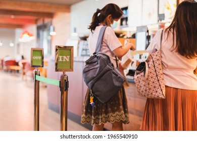 Foucs On Entry And Exit Sign Barrier Stanchion Queue With Woman At Cafe Counter