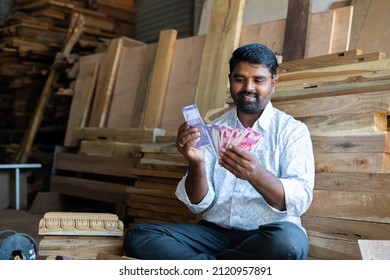 Foucs On Face, Happy Young Indian Woodworker Or Carpenter Counting Money At Workplace Or Shop - Concept Of Carpentry Service, Earning, Professional Occupation, Financial And Banking.