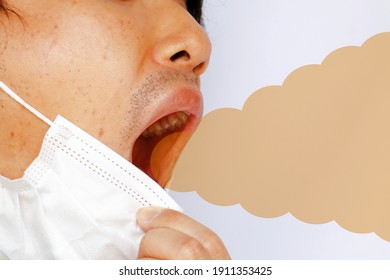 Foul Odor Emitted From The Mouth Of A Japanese Man Who Removes His Mask. Image Of Halitosis.