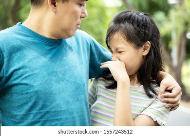 Foul-smelling man was hugging her daughter while her child girl can smell the armpit smelly or the body odor foul from her father with closing her nose,feel stinks,asian male sweat from hot weather