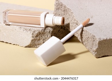 Foundation, concealer on the background of stone geometric shapes. Face corrector on beige background with copy space. Packaging mockup with copy space
