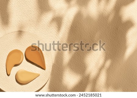 foundation samples on glass with shadows and warm backdrop