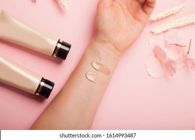 Foundation swatches on hand, testing different shades. Two tubes lying near the hand on pink background
 - Shutterstock ID 1614993487