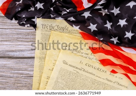 Founding of Independence US documents are laid out on waving American flag, symbolizing national pride.