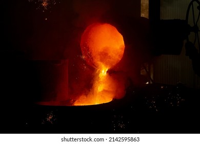 Foundry. Pouring Hot Metal From A Ladle Into Molds. Bright Red Metal And Sparks Flying To The Sides