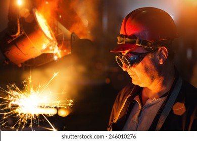 Foundry Worker Looking At Sparks In The Front Of The Molten Steel.