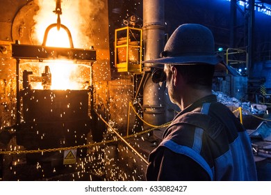  Foundry Worker Pouring Hot Metal Into Cast. Molten Metal. Left Over Material From The Steel Manufacturing Process Is Poured Away On At A Steel Foundry