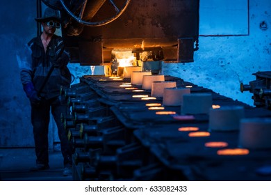  Foundry worker pouring hot metal into cast. Molten metal. Left over material from the steel manufacturing process is poured away on at a Steel Foundry, molds in foreground - Powered by Shutterstock