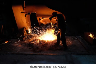 Foundry Worker Removing Molten Metal Impurity.