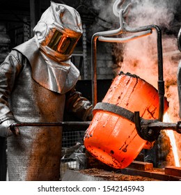 In a foundry workshop. A worker protected by a safety suit pours the molten metal into a mold - Powered by Shutterstock