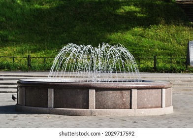 Fountain in the city square. View of the fountain against a background of green grass.