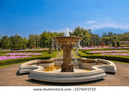 The fountain in a garden with blooming flower fields and ornamental plants at the natural tourist attraction 'Taman Bunga Nusantara', Bogor, Indonesia