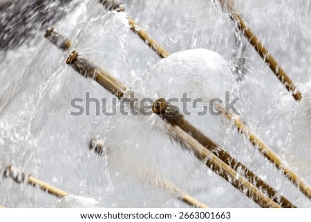 A fountain with many small water spouts shooting out of it. The water is white and the spouts are brown
