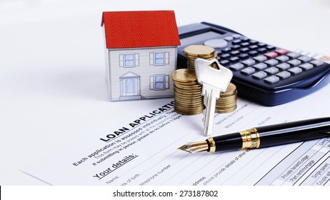 Fountain pen and key and calculator and paper house and coins stack on Loan Application form for Mortgage loans concept