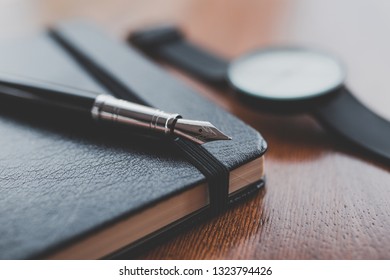 A fountain pen on a notebook near a watch - Powered by Shutterstock