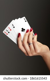 Four aces playing cards in woman's hand. Player with poker quads combination. Elegant female hands with red manicure on nails.