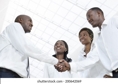 Four African Business Partners Shake Hands, Studio Shot