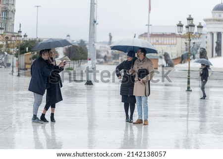 Four amazing business people are standing and talking to each other out on the rain