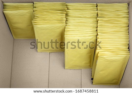Four ascending rows of bubble envelopes inside a big cardboard box.