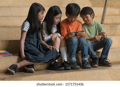 Four asian children,boy and girl sit on stair at school,play hand together,fun and happy,education concept,learning and knowledge.