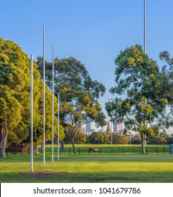 Four Australian Football Goal Posts At A Football Oval In Carlton, With The City Buildings Of Melbourne, Australia In The Distant Background