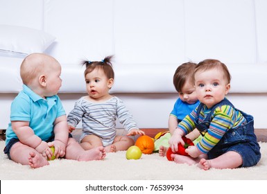 Four babies group sitting on the floor