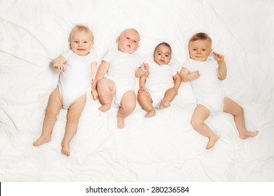 Four babies lay in a row on the white background