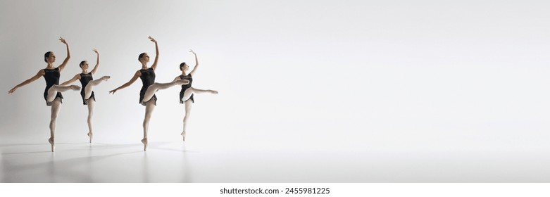 Four ballet dancers, teen girls in black leotards dancing against grey studio background. Synchronization. Ballet, art, dance studio, classical style, youth concept. Banner. Empty space to insert text - Powered by Shutterstock