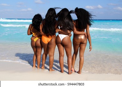 Four beautiful African American beautiful young girls in thong bikinis on a Caribbean beach. 