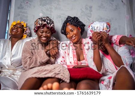 Four beautiful African girlfriends wearing hair bonnet and robes,laughing and having fun on vacation holidays,treatment at spa - Black Pretty bridesmaids indoors looking cheerful