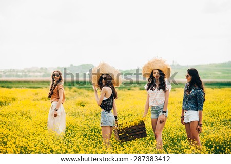 four beautiful hippie girl in a field of yellow flowers