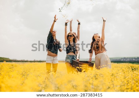 four beautiful hippie girl in a field of yellow flowers