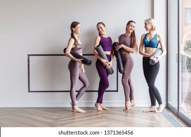 Four beautiful slim positive young girls fitness models are preparing for joint training and rejoice at the meeting. The concept of sports lifestyle and like-minded people. Yoga concept