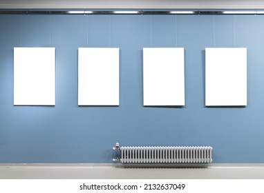 Four Blank White Vertical Posters Hang On Blue Wall In An Exhibition Hall. Empty Interior, Front View, Background Photo