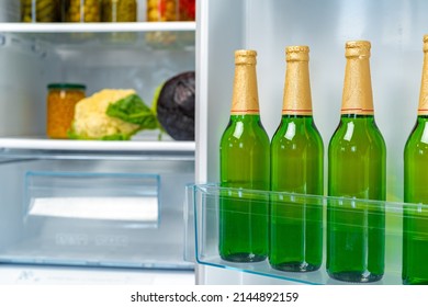 Four Bottles Of Beer On Shelf In Fridge