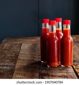 Four Bottles Of Hot Sauce On Wooden Table