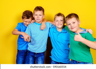 Four Boys Best Friends Standing Together. Bright Yellow Background. Summer Fashion.
