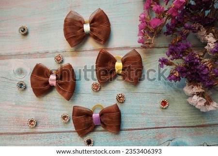 four brown bows lie on a blue wooden table next to a decor of dry flowers. view from above . hair accessories . bow