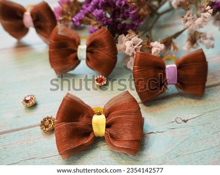 four brown bows lie on a blue wooden table next to a decor of dry flowers. hair accessories . bow