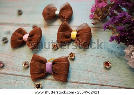four brown bows lie on a blue wooden table next to a decor of dry flowers. side view . hair accessories . bow