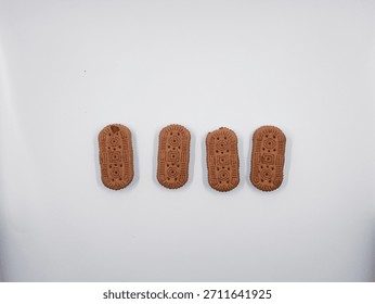Four brown rectangular biscuits featuring intricate geometric patterns are neatly aligned across a bright white surface suggesting a simple snack concept or food product display with ample copy space.