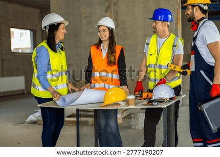 Four builders and architects collaborating on project details with professional tools and spirit level. Perfect for teamwork, industrial management, and gender diversity themes.