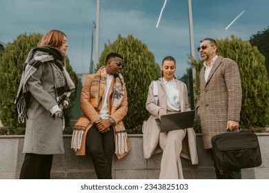 Four business colleagues working outside while sitting - Powered by Shutterstock