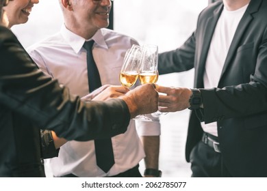 Four Business Partner Celebrating Their Victory. Old Business Man Making A Toss To Younger Business Man And Woman. They Are Holding A Champagne Glass In A Hotel Lobby With City Scape Background.