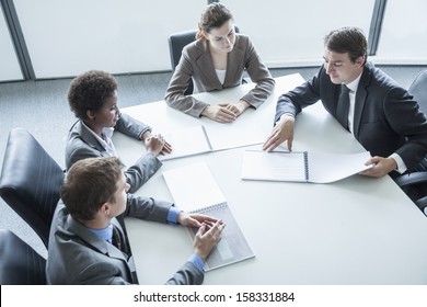 Four Business People Sitting Around Table And Having Business Meeting