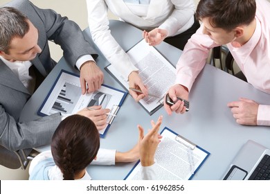 Four businesswomen sitting at table examining some documents