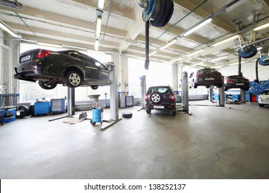 Four cars on lifts and on floor in small service station. Cars prepared to diagnosis and repair.