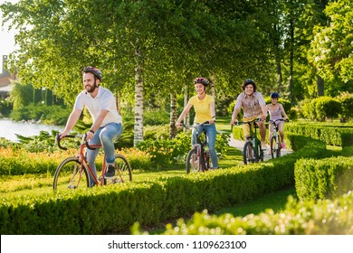 Four cheerful friends cycling outside. Group of young happy persons riding bicycles outdoors. Summer leisure with bicycles.