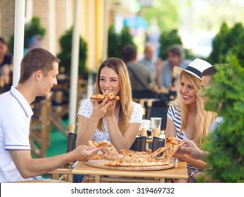 Vier fröhliche junge Freunde teilen Pizza in einem Café im Freien